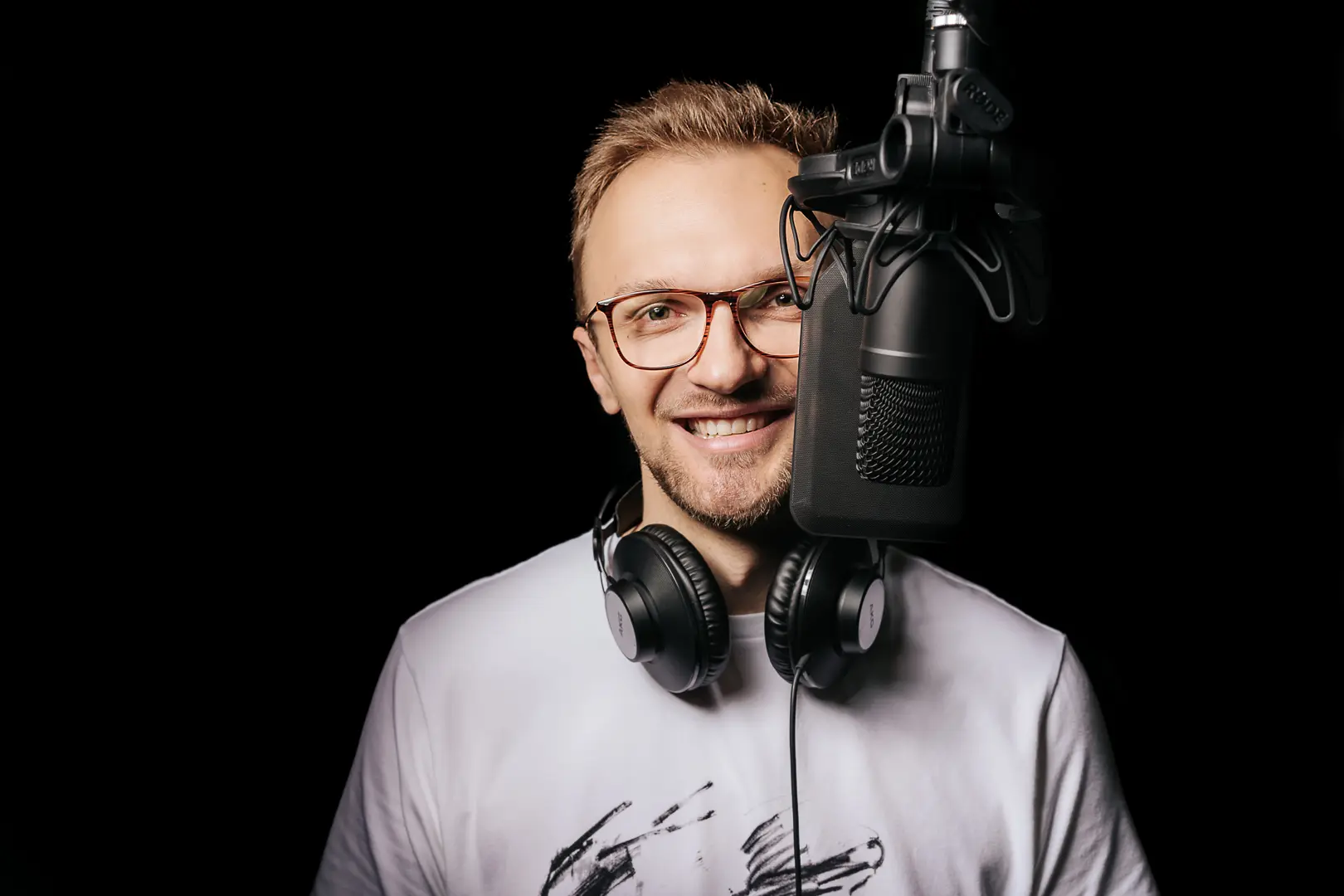 Maciej Motylski uśmiecha się zza mikrofonu